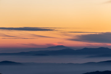 Beautifully colored sky at dusk, with mountains layers and mist between them