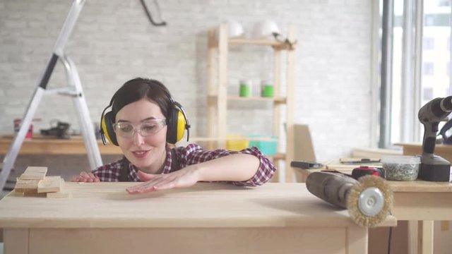 Closeup young professional carpenter woman blows wood shavings from the table