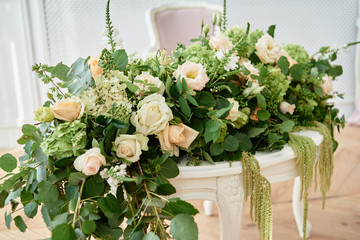 Luxury floral arrangement of pink and beige roses, freesia, hydrangea and amaranth on white wood...