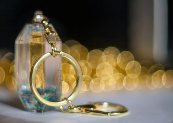 Glass key chain with gold chain and ring on a blurred background with a beautiful bokeh from the beads