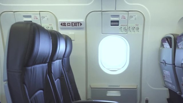 Passenger seats and emergency exit door inside commercial airplane. Interior modern passenger aircraft, passengers chairs and emergency door exit. Economy class cabin airplane.