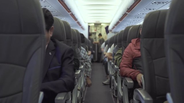 Passengers sitting on seats aircraft while flying in sky. Passengers inside cabin commercial plane while flight. Air traveling by modern commercial airplane.