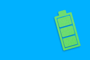 One handmade paper icon of full battery on blue table. Top view. Green energy concept. Copy space for your text