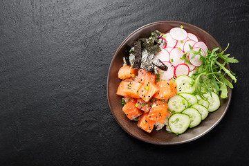 Salmon fish poke bowl with rice, radish,cucumber, tomato, sesame seeds and green onion.
