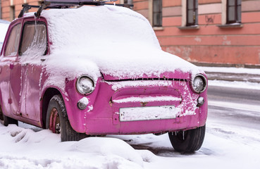 Old vintage pink Car covered by Snow in Winter Time