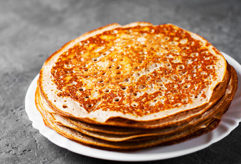 Stack of kefir pancakes in white plate on Dark grey black slate background