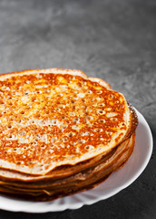 Stack of kefir pancakes in white plate on Dark grey black slate background