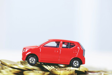 Little toy red car over a lot of money stacked coins. for  bank loans costs finance. insurance, buying car finance concept. buy and pay by installments down payment a car. soft focus.