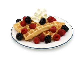  fresh belgian waffles with raspberrys, blackberries  and whipped cream on a plate isolated on white background