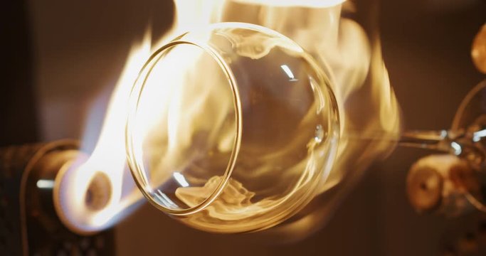 Slow motion macro of experienced glass blower working with flame on a handmade wine glass from crystal in a workshop. Shot in 8K. Concept of handmade, high quality, artisan, made in Italy,glass blower