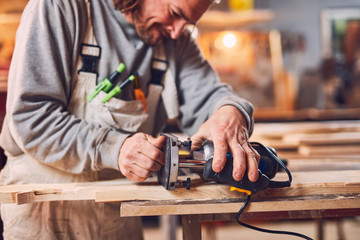 Male carpenter working on old wood in a retro vintage workshop.