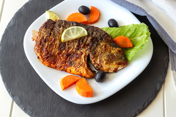 Grilled fish sea bream with vegetables on white plate. White background. Healthy diet food concept.