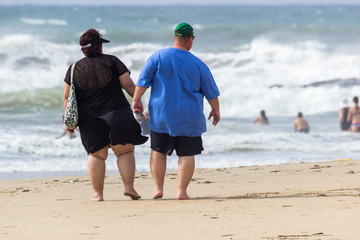 overweight couple walking on the beach