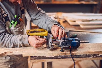 Male carpenter working on old wood in a retro vintage workshop.