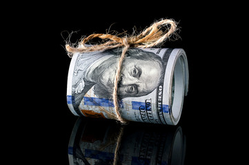 Rolled up dollar bills on black reflective background.