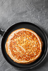 Stack of kefir pancakes in iron pan on Dark grey black slate background