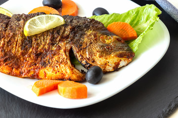 Grilled fish sea bream with vegetables on white plate. White background. Healthy diet food concept.