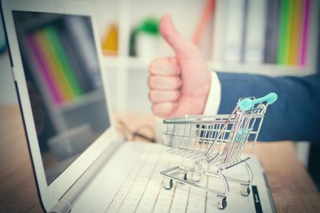 businessman with miniature shopping cart in the office, shopping and sales concept