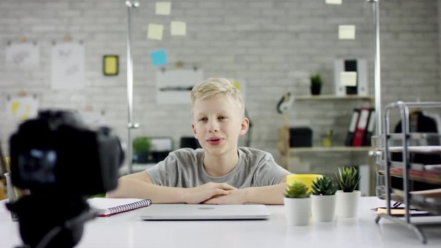 Genius boy wonder hacks system at cyberspace. Cute kid young programmer developer working on computer at office. He is looking in the cam and speaking