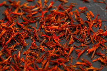 Bright red orange dried saffron (Crocus sativus) flowers on black board.