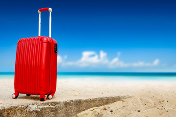 Summer red suitcase on beach and sea landscape. Free space for your decoration. Summer time 