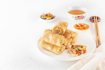 Traditional Chinese tortillas filled - bings in a plate on a white background, salads, Dam Sam snacks and cup of tea. Copy space