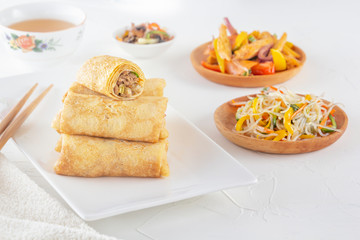 Traditional Chinese tortillas filled - bings in a plate on a white background, salads, Dam Sam snacks and cup of tea.