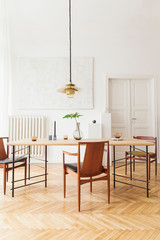 Eclectic and elegant dining room interior with design sharing table, chairs, gold pedant lamp,...
