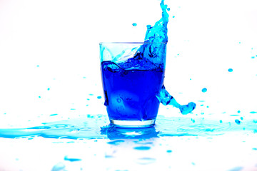Blue water splash in glass isolated on white background