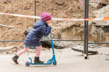 Obraz na płótnie Canvas little girl on scooter at the fence