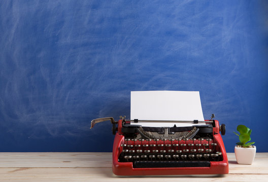 writer's workplace - red typewriter on blue blackboard background