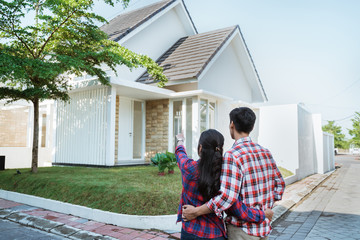 back portrait of young couple standing in front of their new house
