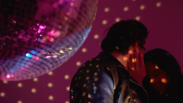 Playful drunk couple making out at party in night club, passionate kiss at disco