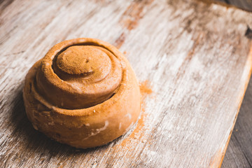 Cinnamon bun on the wooden background. Selective focus.