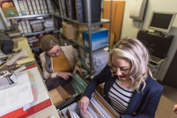 wide angle of attractive office woman working looking files in basement - obrazy, fototapety, plakaty