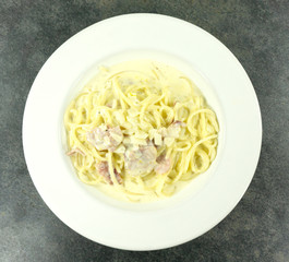 Close up Spaghetti Carbonara in a White plate on a stone floor table.