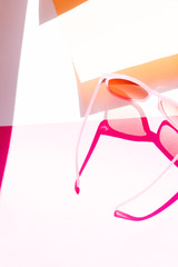 Pink plastic sunglasses on pink and yellow background. Pop art conception.