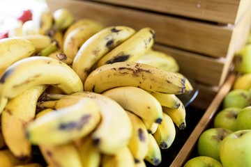 Close up of fresh and ripe yellow bananas in a wooden crate beside some on a market stall