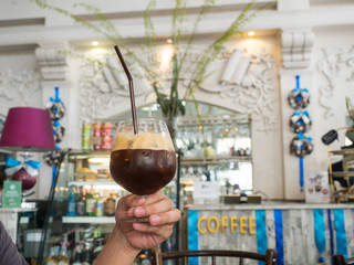 man holding glass of ic black coffee on his hand in coffee cafe