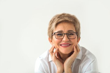 portrait of stylish aged woman with glasses and short haircut on a white background