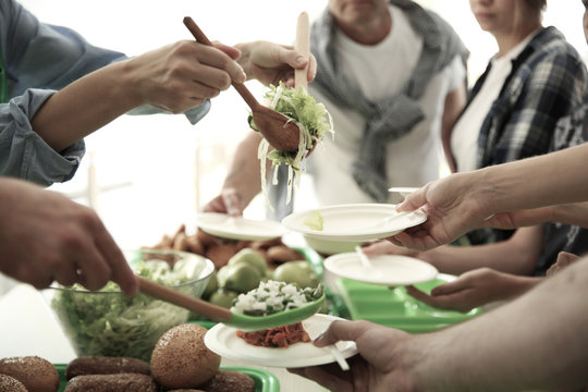 Volunteers serving food for poor people indoors