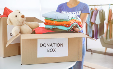 Female volunteer collecting donations at table indoors