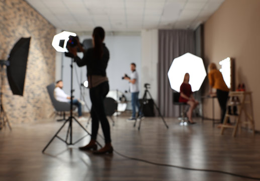 Blurred photo studio with professional equipment and team of workers