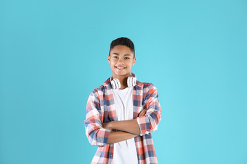 Portrait of African-American teenage boy with headphones on color background