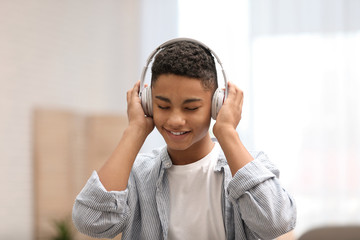 African-American teenage boy listening to music with headphones at home