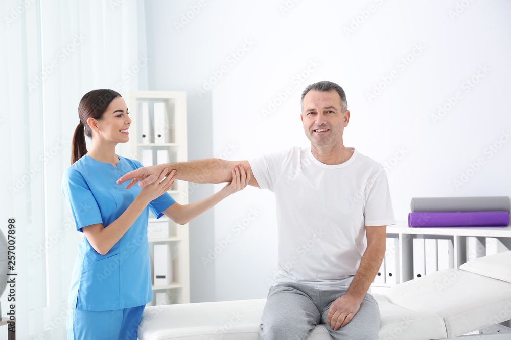 Poster Doctor working with patient in hospital. Rehabilitation physiotherapy