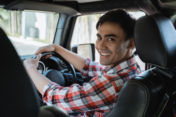 male driver looking at the back while driving his car