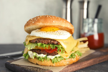 Tasty burger with fried egg on wooden board