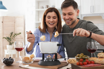 Happy couple enjoying fondue dinner at home