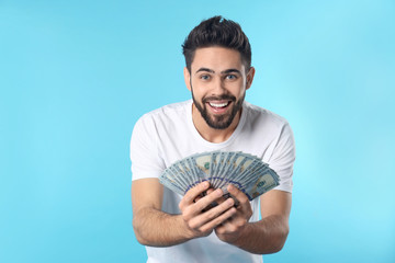 Portrait of happy young man with money on color background